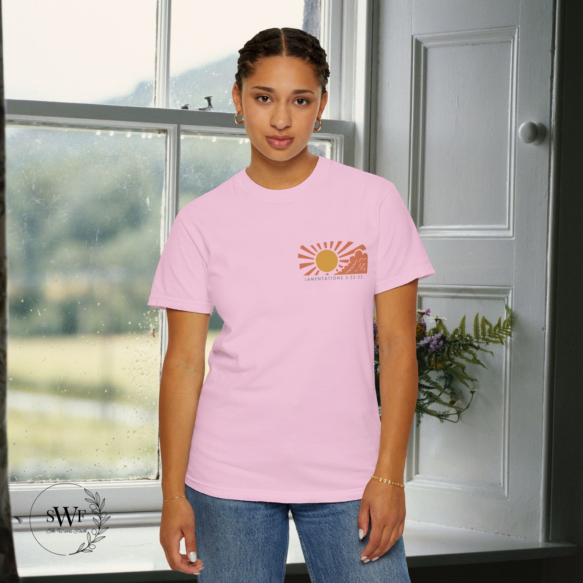 Person wearing a pink t-shirt with a sun graphic design indoors.