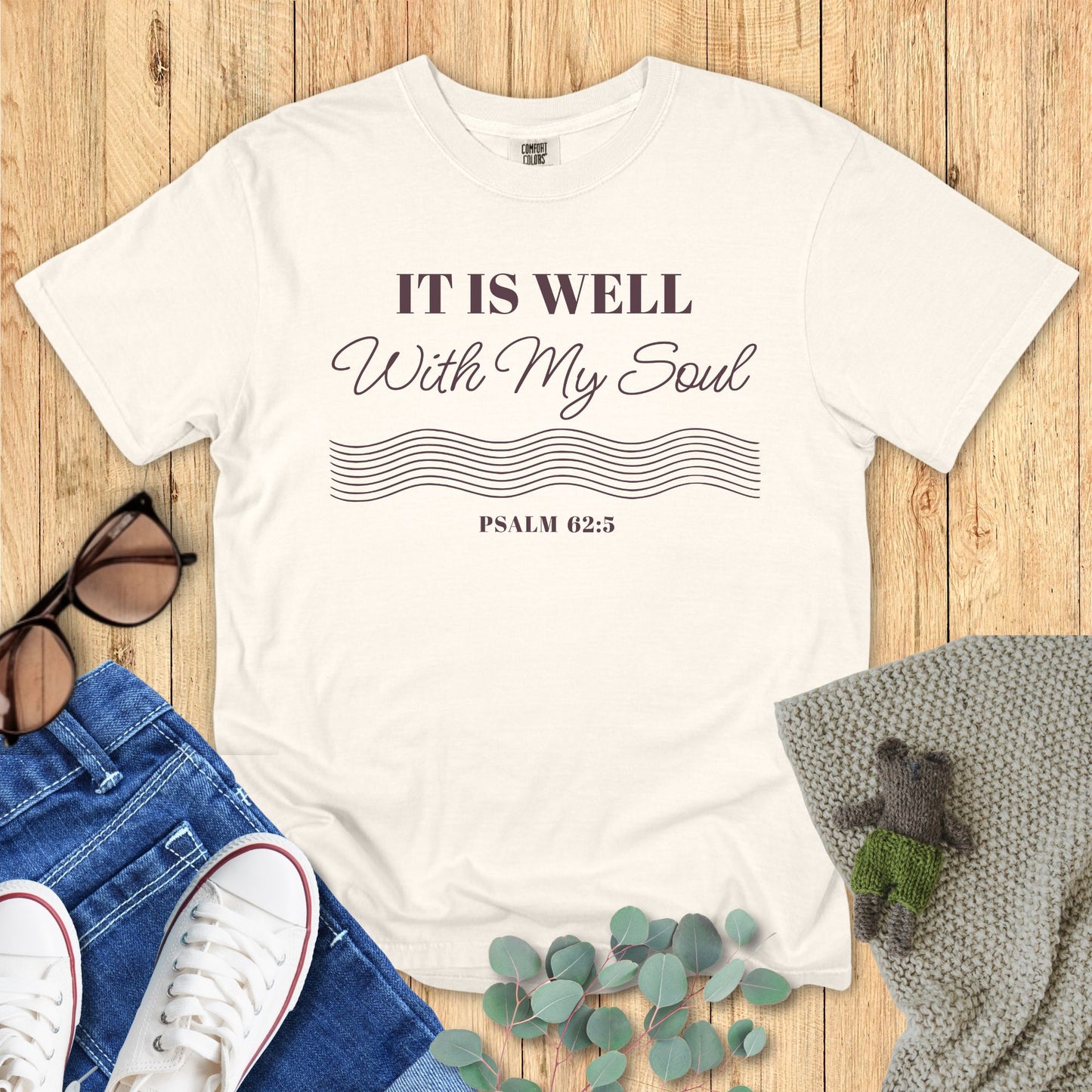 Ivory White t-shirt with 'It is Well with My Soul' text on a wooden surface with accessories.