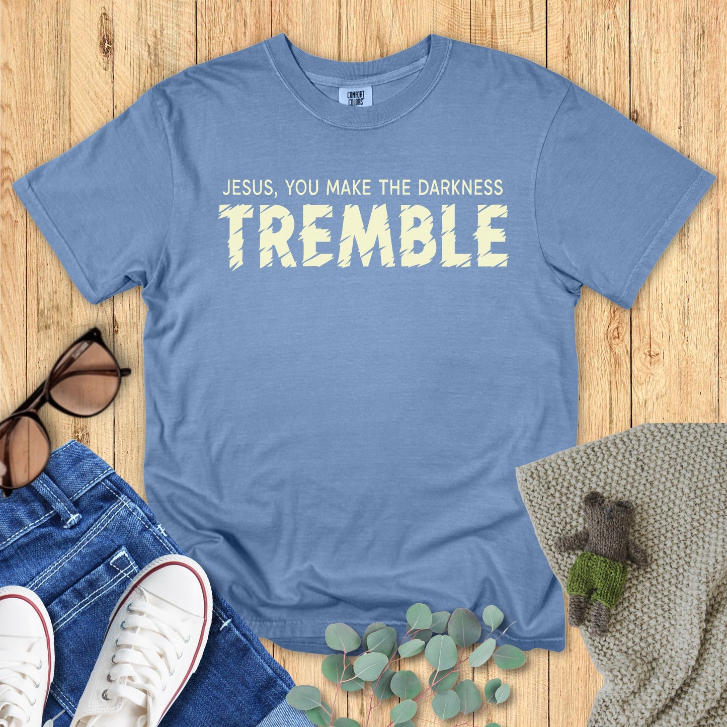 Blue t-shirt with the phrase “Jesus, You Make the Darkness TREMBLE” in bold cream-colored text