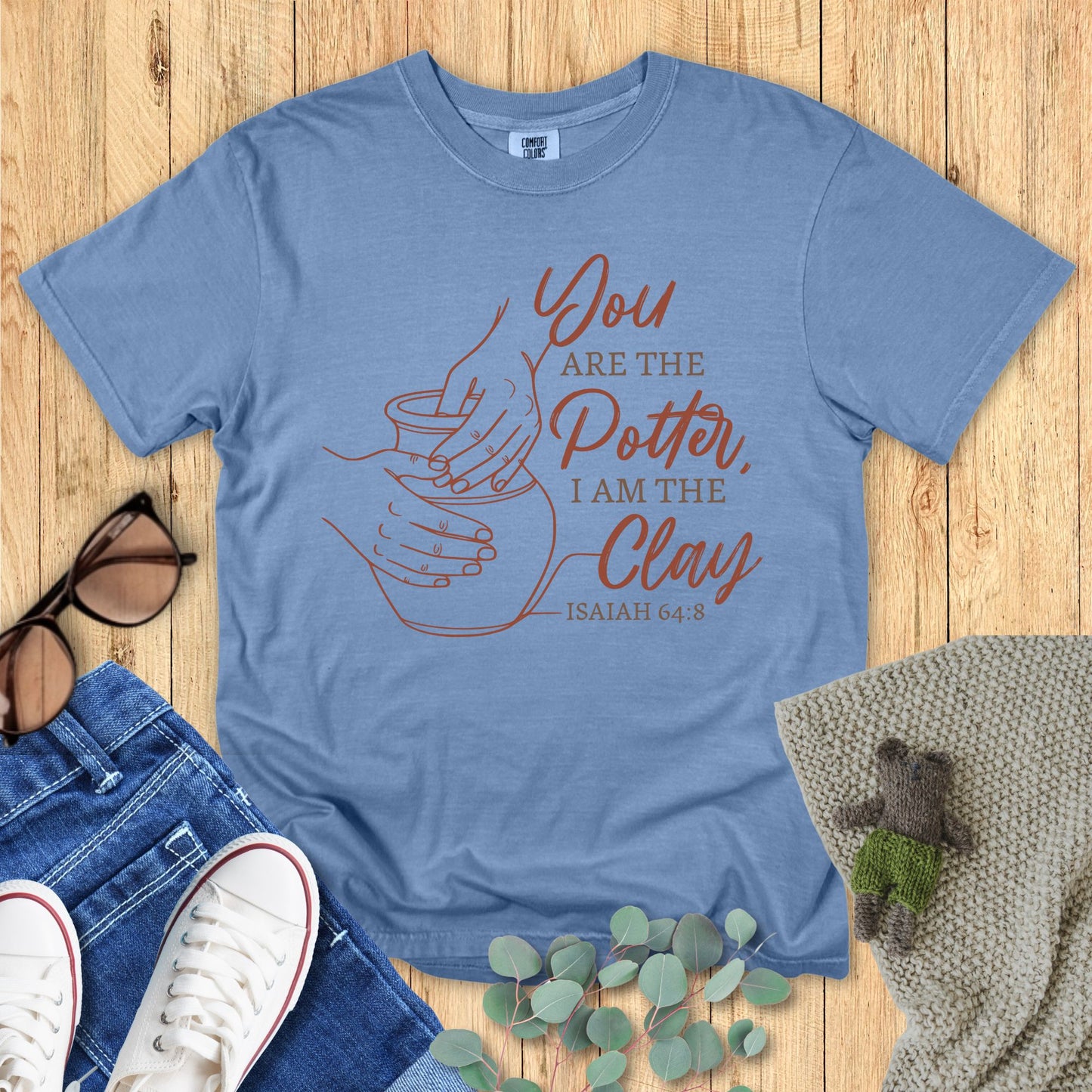 Blue t-shirt with a motivational quote on a wooden surface with accessories.