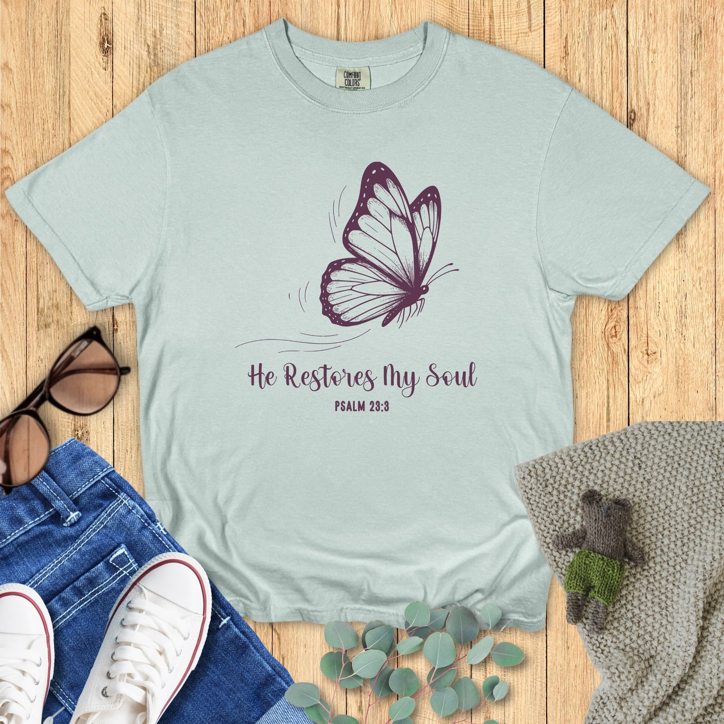 Light blue t-shirt with a purple butterfly and the phrase “He Restores My Soul – Psalm 23:3” in script lettering.