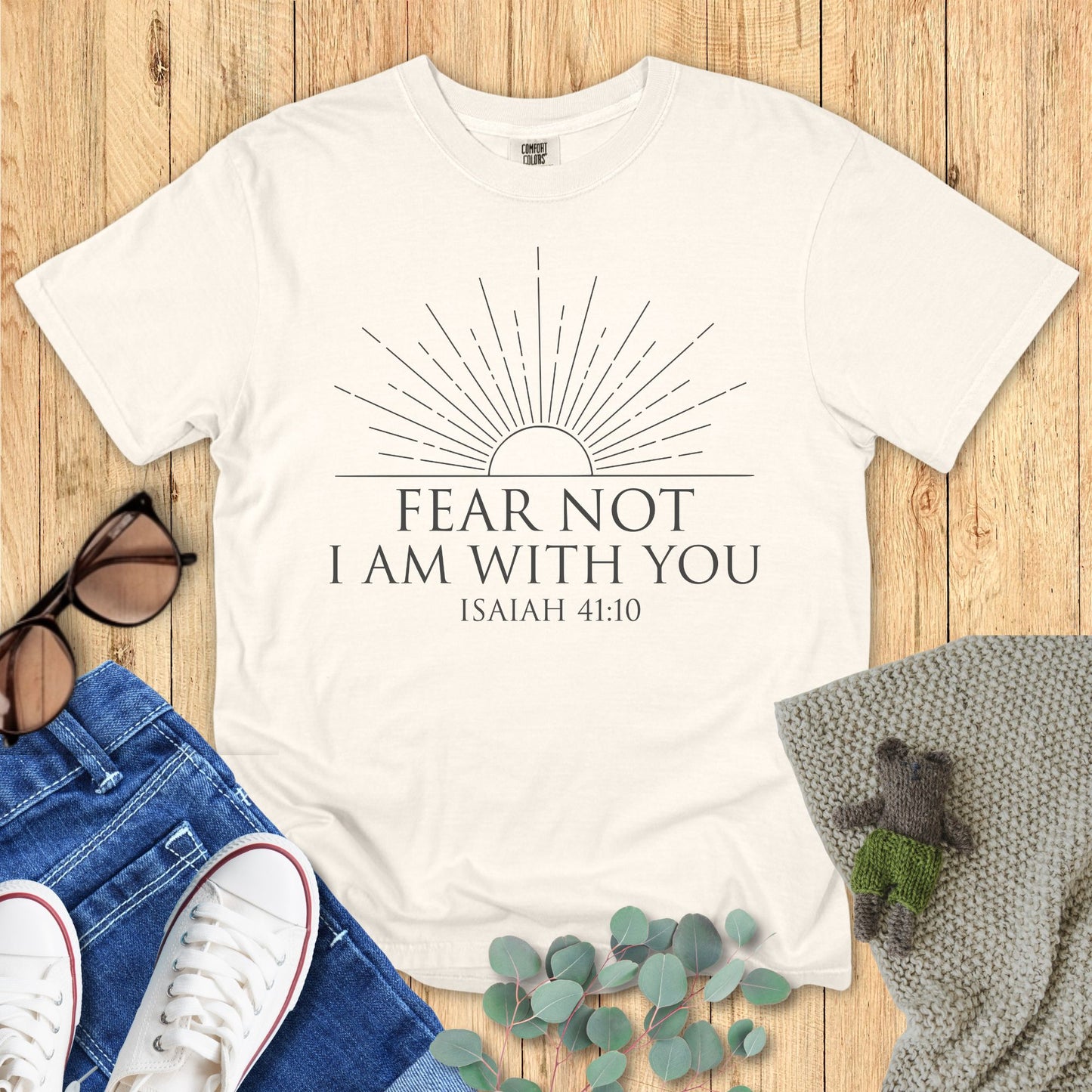 Ivory White t-shirt with 'Fear Not, I Am With You' text on a wooden surface with accessories.