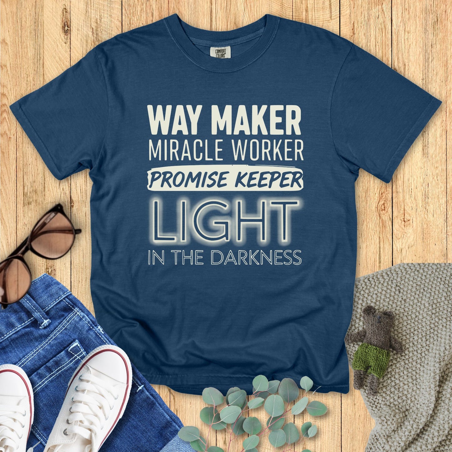 Blue t-shirt with motivational text on a wooden surface with accessories.