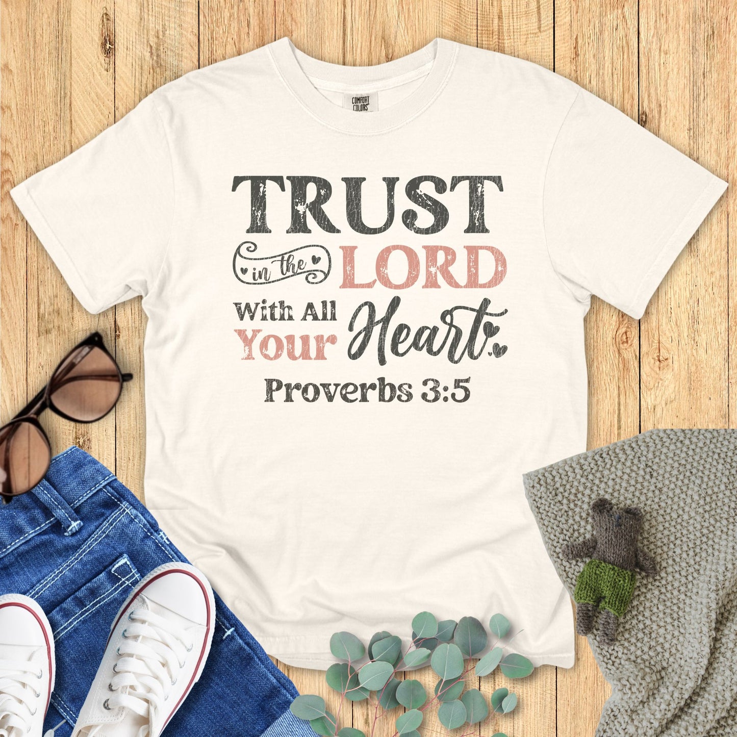 IVory White t-shirt with motivational quote on a wooden surface with casual items.