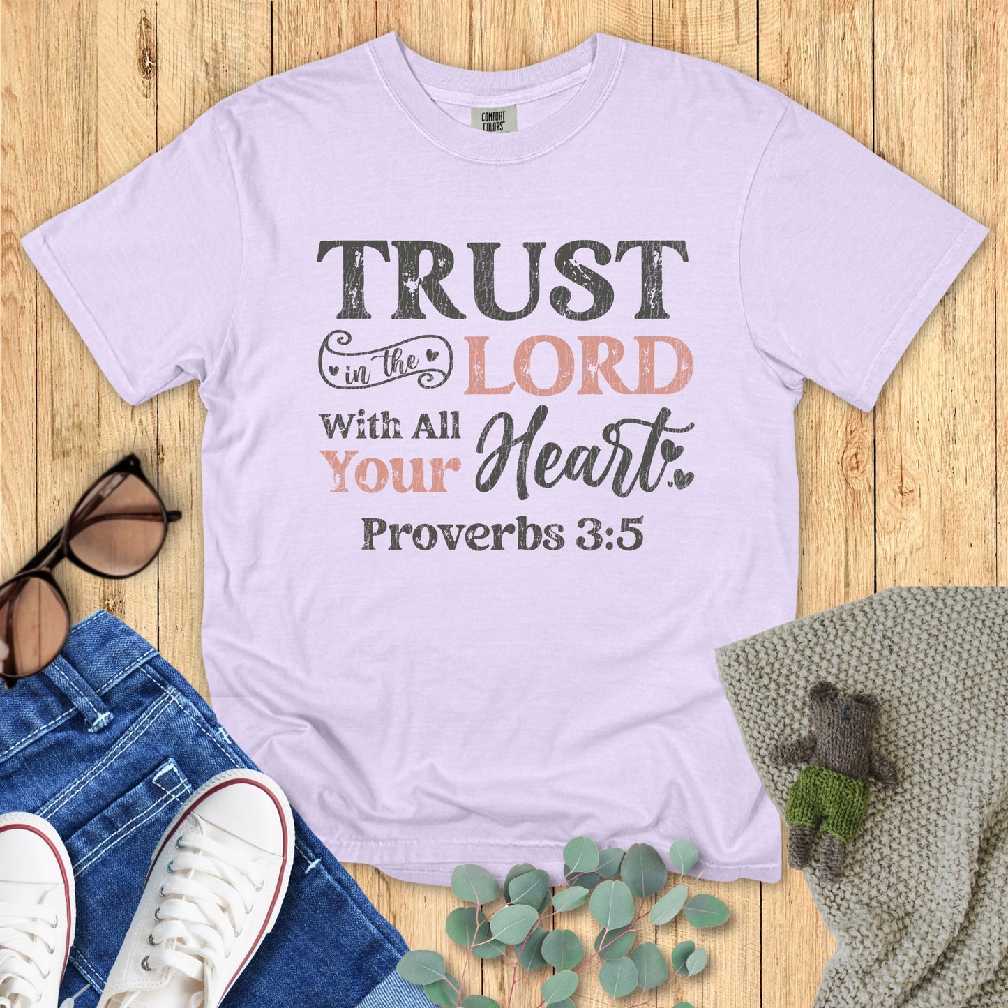 Lavender t-shirt with motivational quote on a wooden surface with accessories.