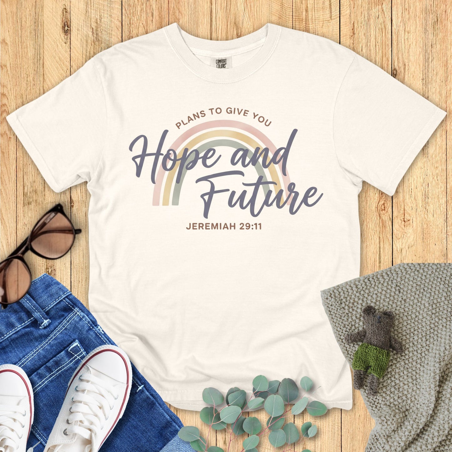 White t-shirt with motivational quote on a wooden surface with accessories.
