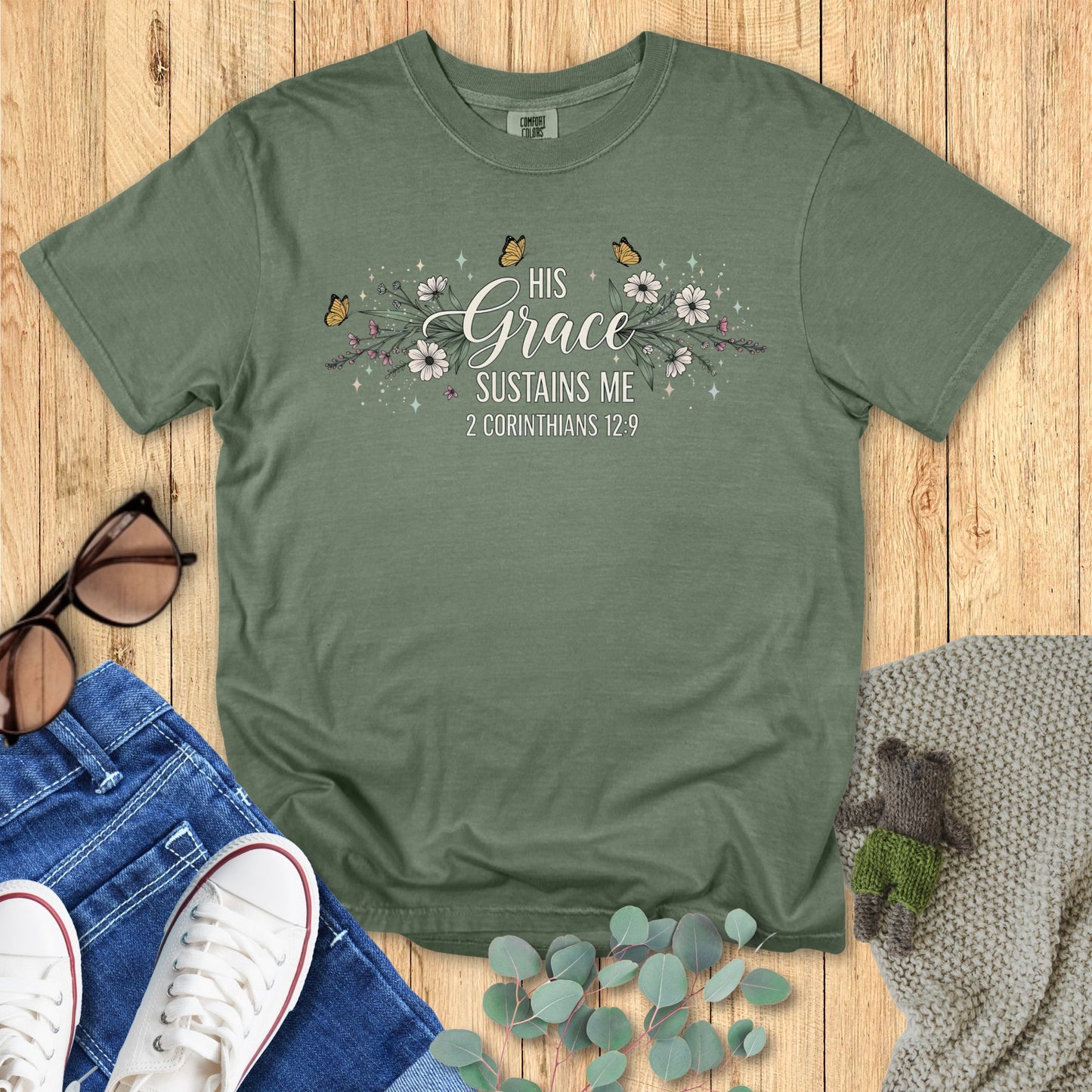 Green t-shirt with motivational quote on a wooden surface with accessories.