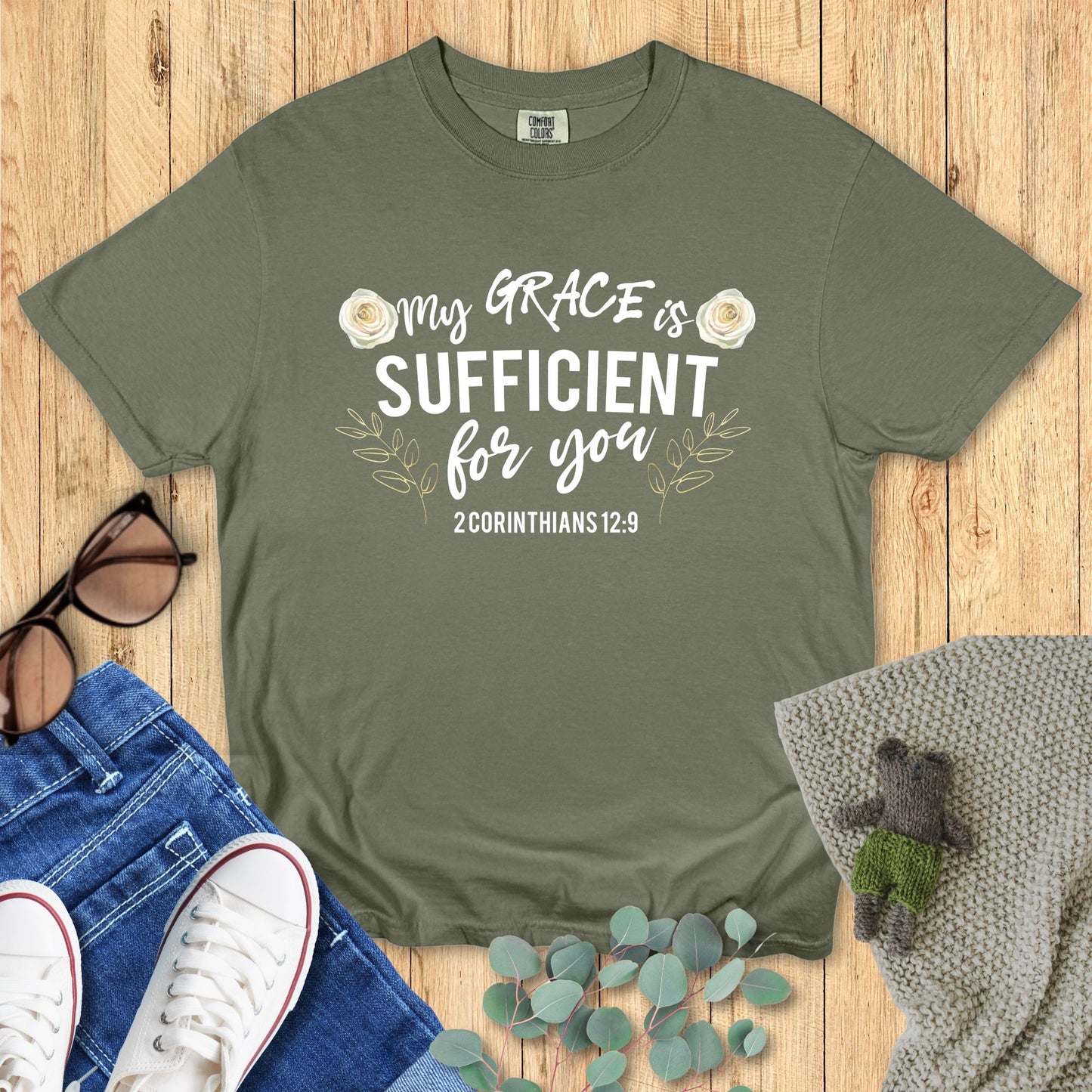 Green t-shirt with motivational quote on a wooden surface with accessories.