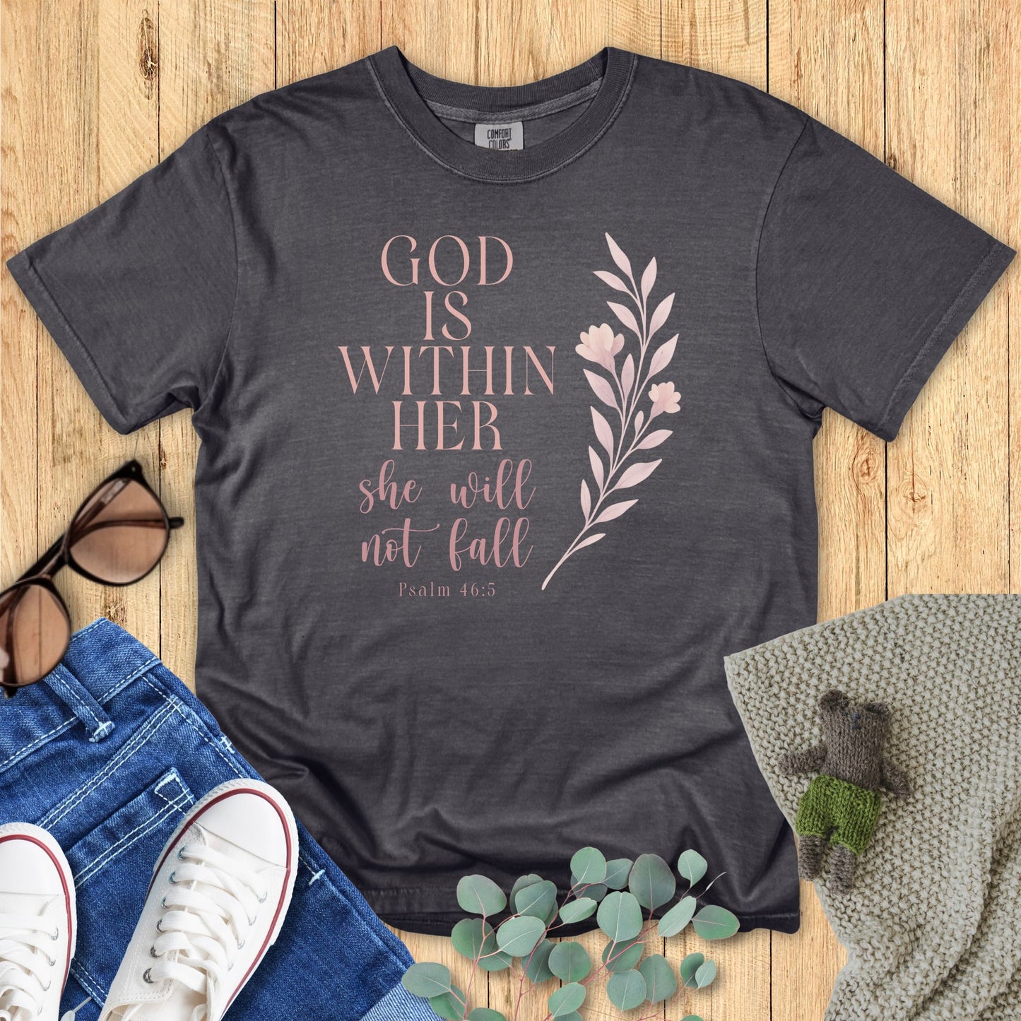 Dark gray t-shirt with motivational quote on a wooden surface with accessories.