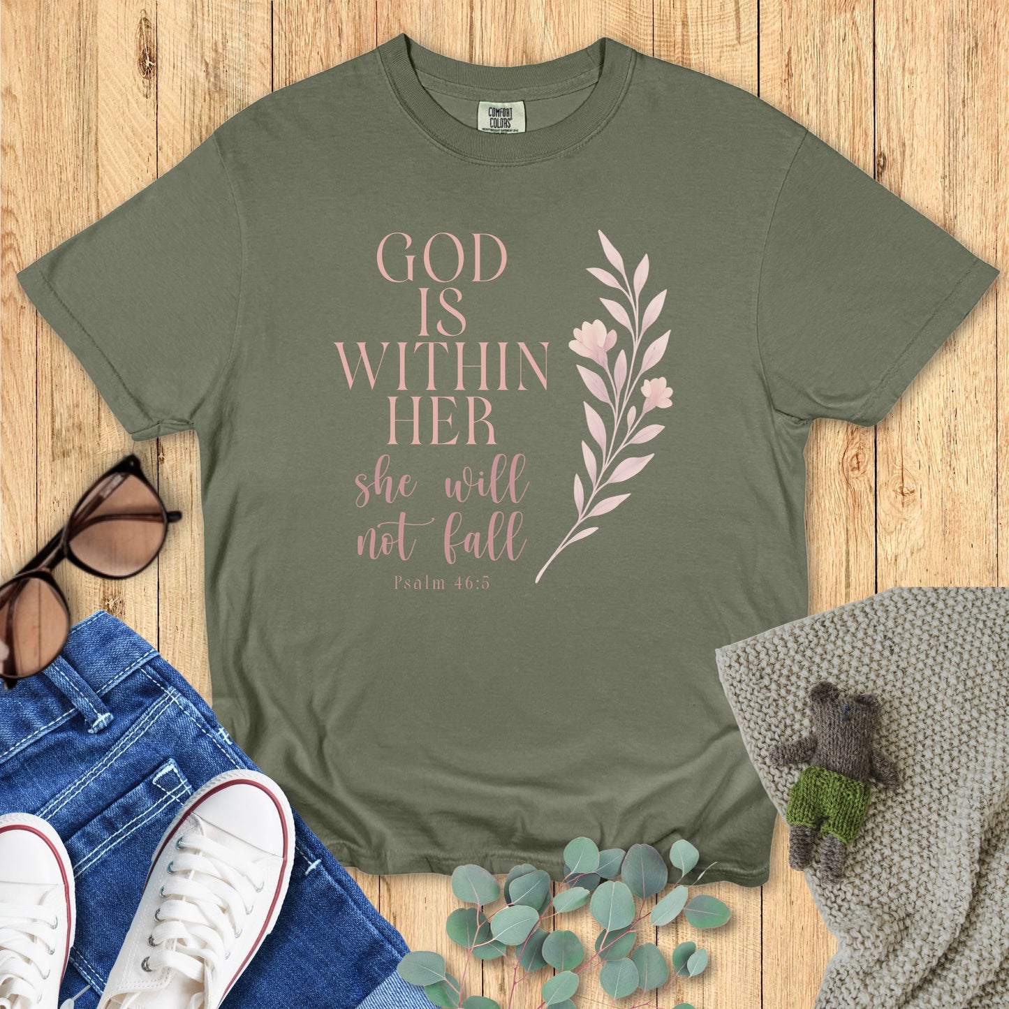 Green t-shirt with motivational quote on a wooden surface with accessories.