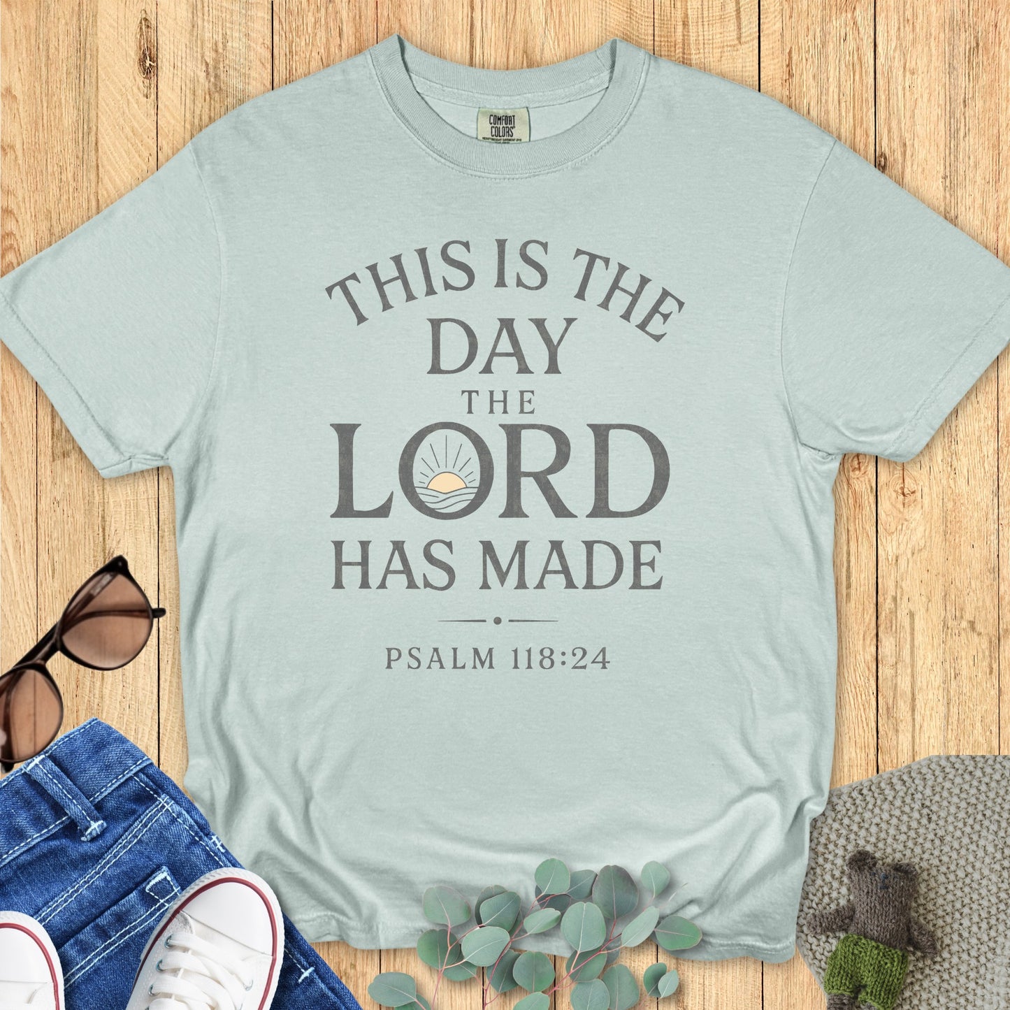 Comfort Colors 1717 bay blue “This Is The Day The Lord Has Made – Psalm 118:24” t-shirt with minimalist sunrise artwork. A modern Christian shirt that inspires daily thankfulness and faith.