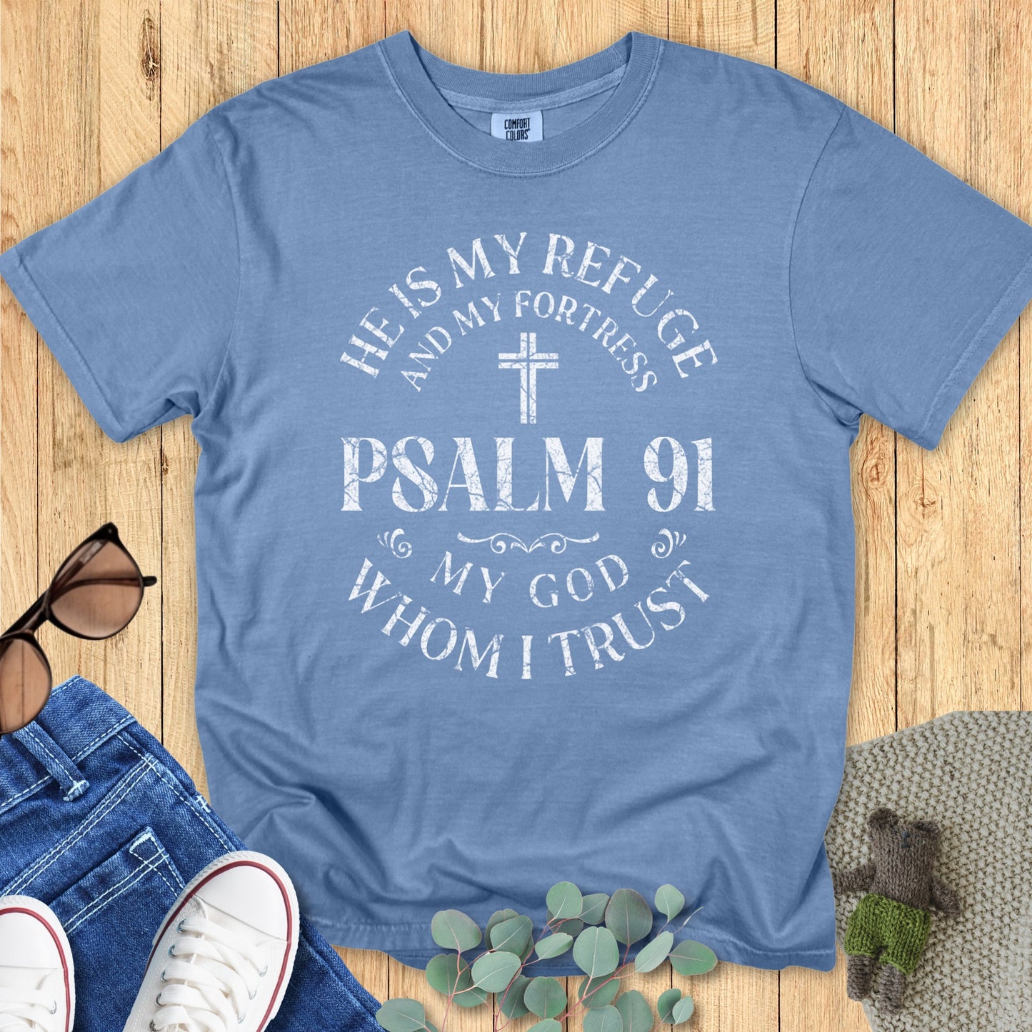 Comfort Colors 1717 blue jean “He Is My Refuge and My Fortress – Psalm 91 My God Whom I Trust” t-shirt featuring a distressed vintage cross print. A stylish modern Christian shirt and everyday women’s scripture tee for faith-filled living.
