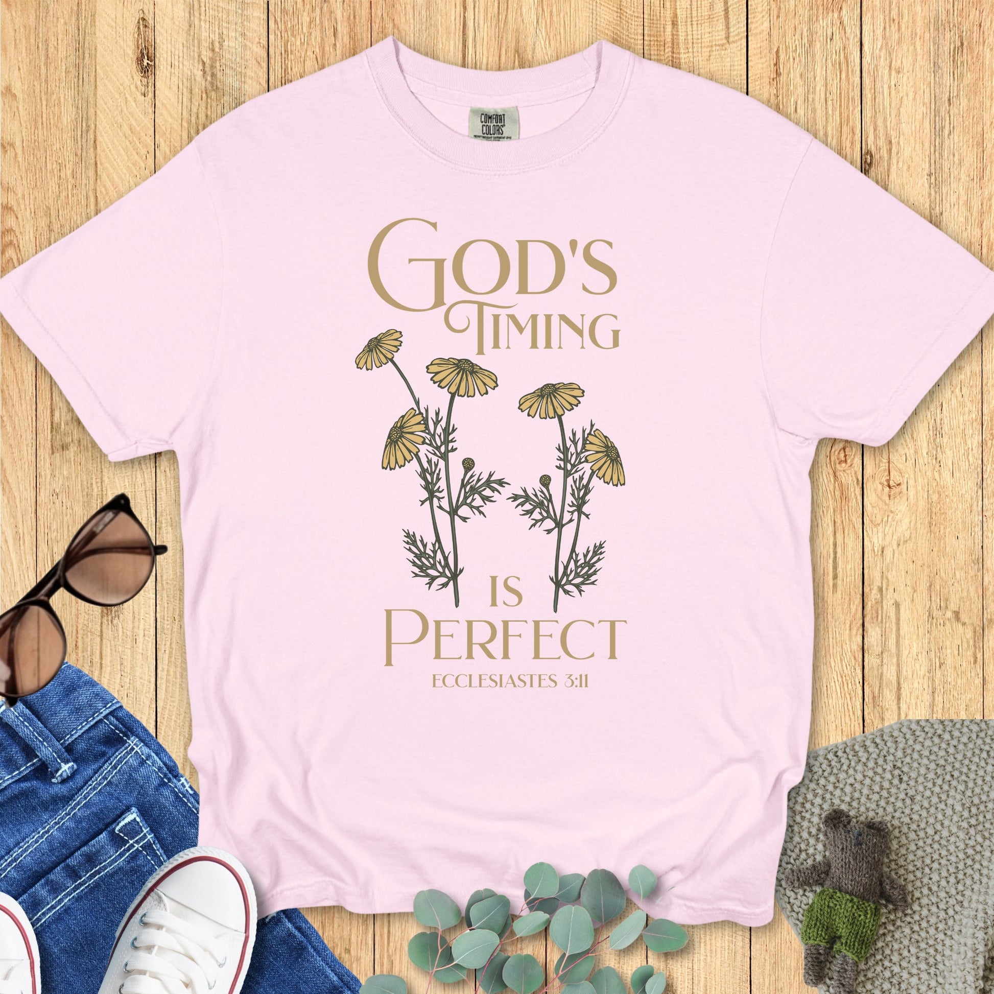 Flatlay of a Comfort Colors 1717 blossom “God’s Timing Is Perfect – Ecclesiastes 3:11” t-shirt featuring delicate yellow wildflowers and elegant serif text. A soft, feminine women’s scripture tee — inspiring faith-based apparel for women and thoughtful Christian mom gift idea.