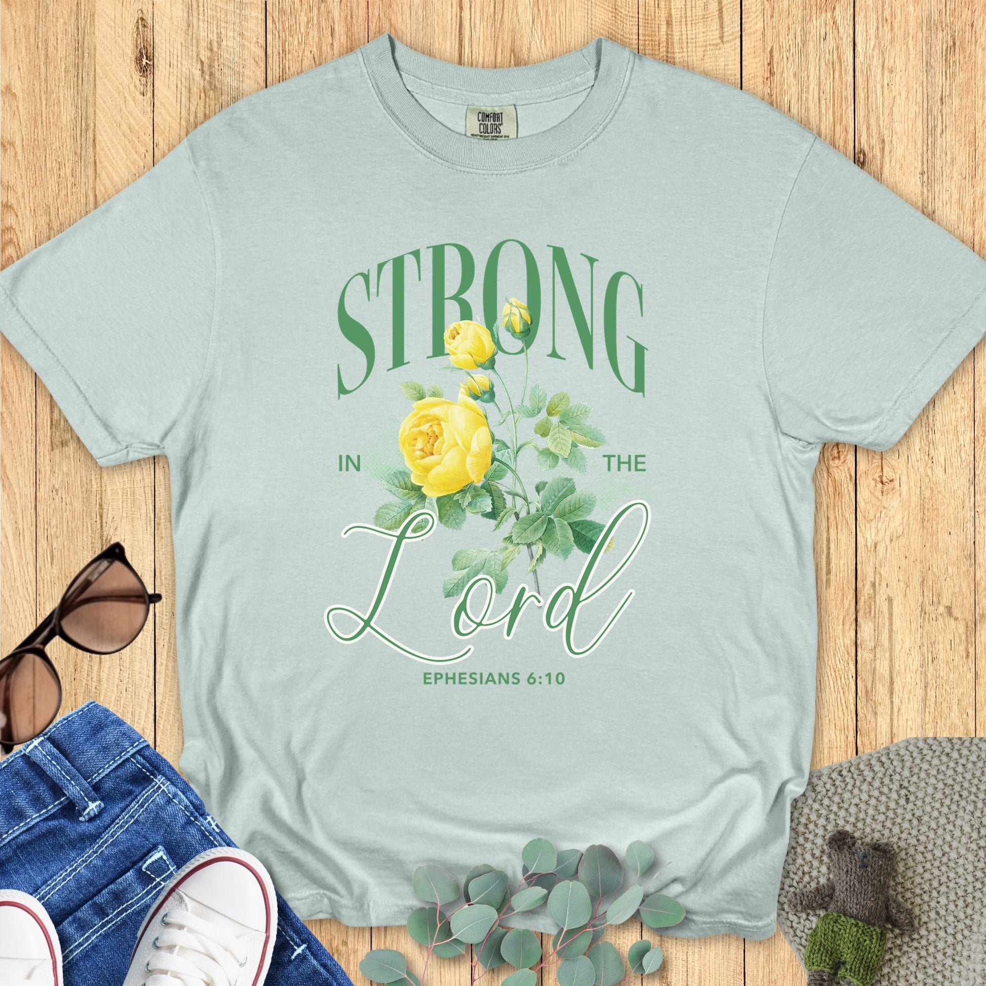 Comfort Colors 1717 bay “Strong in the Lord – Ephesians 6:10” t-shirt with bright yellow rose artwork and bold green typography. A stylish women’s scripture tee — modern Christian shirt and encouraging faith-based apparel for women, ideal Christian mom gift idea.