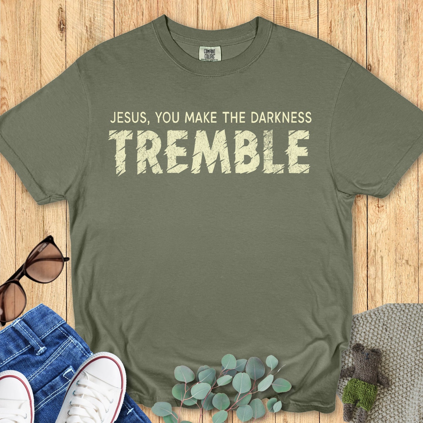 Flatlay of a Comfort Colors 1717 sage “Jesus, You Make the Darkness Tremble” t-shirt with bold distressed text. A faith-filled women’s scripture tee — classic faith-based apparel for women and powerful modern Christian shirt, thoughtful Christian mom gift idea.