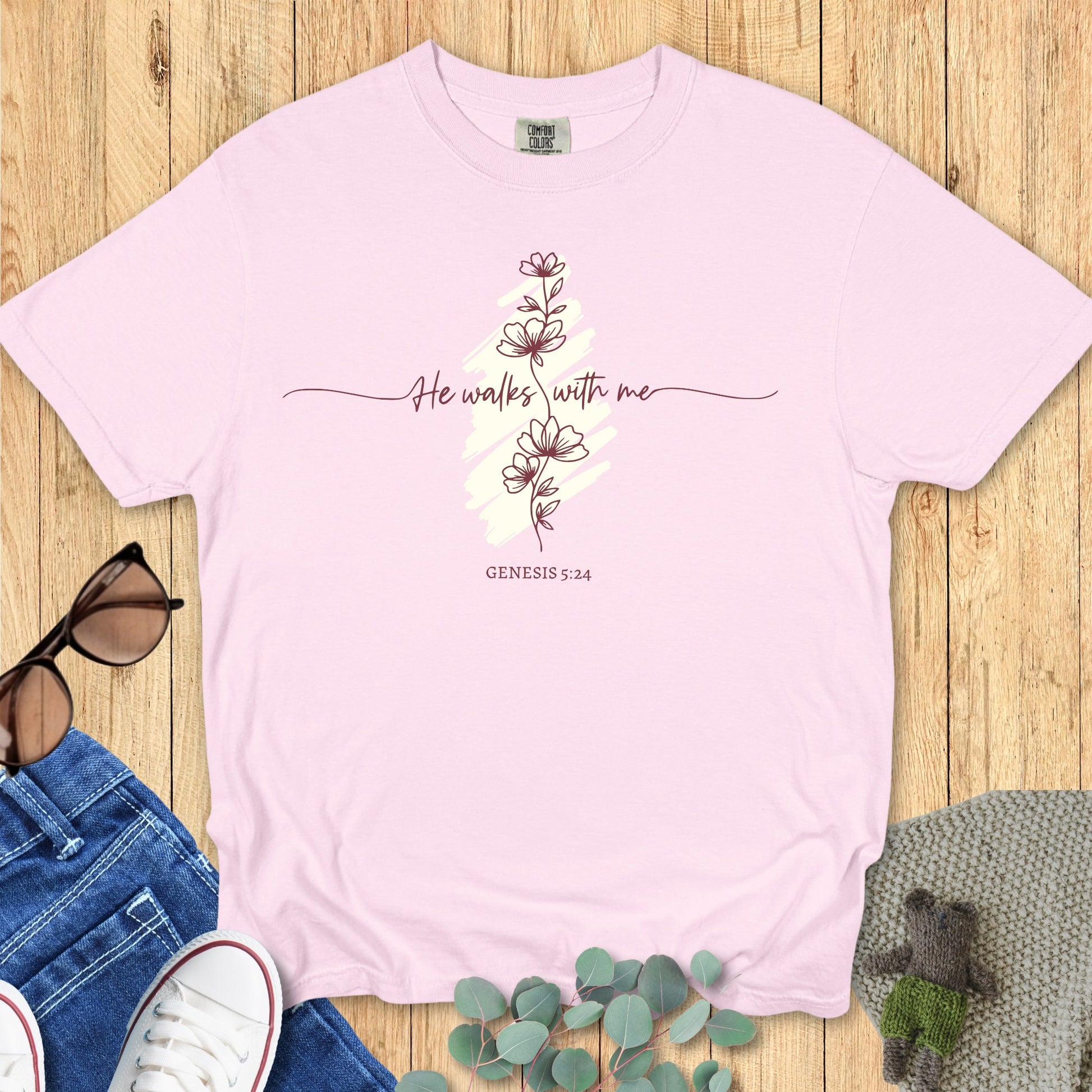Flatlay of a Comfort Colors 1717 blossom “He Walks With Me – Genesis 5:24” t-shirt featuring minimalist flower illustration and soft pastel tones. A beautiful women’s scripture tee — inspiring faith-based apparel for women and modern Christian shirt, perfect Christian mom gift idea.
