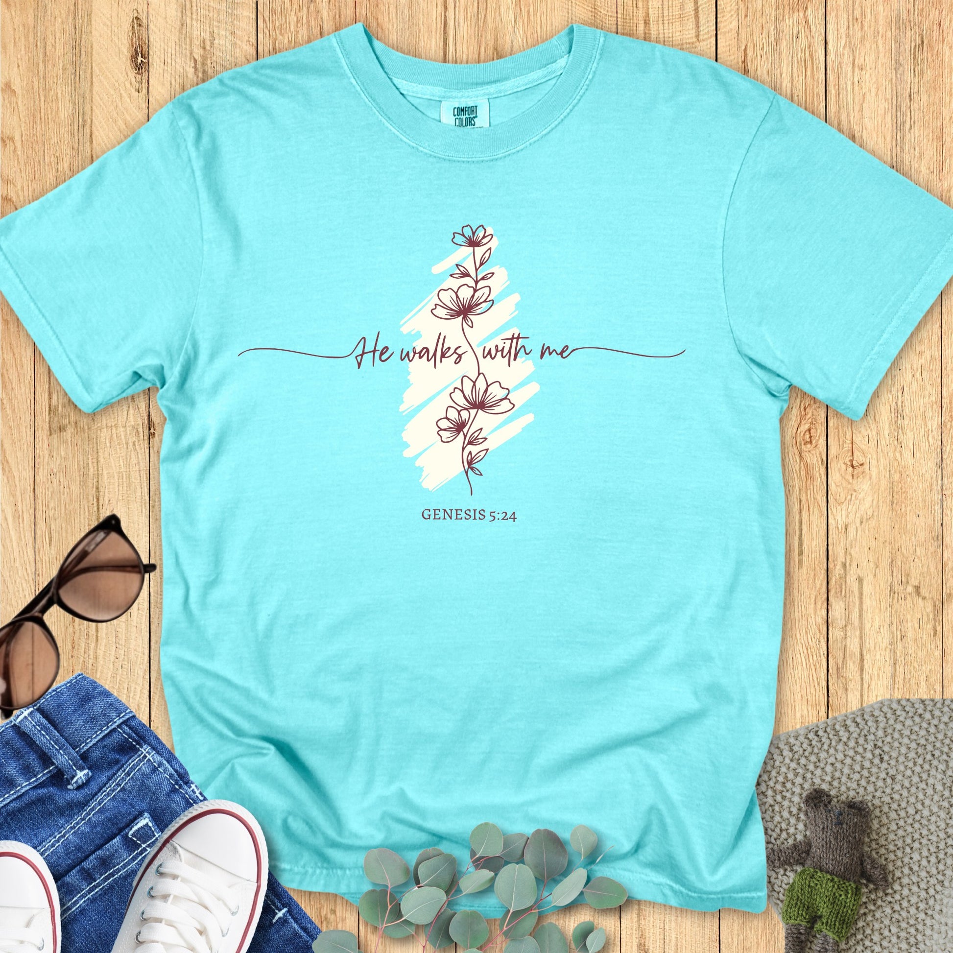 Flatlay of a Comfort Colors 1717 chalky mint “He Walks With Me – Genesis 5:24” t-shirt with delicate floral line art and subtle brush design. A fresh women’s scripture tee — uplifting faith-based apparel for women and stylish modern Christian shirt, meaningful Christian mom gift idea.
