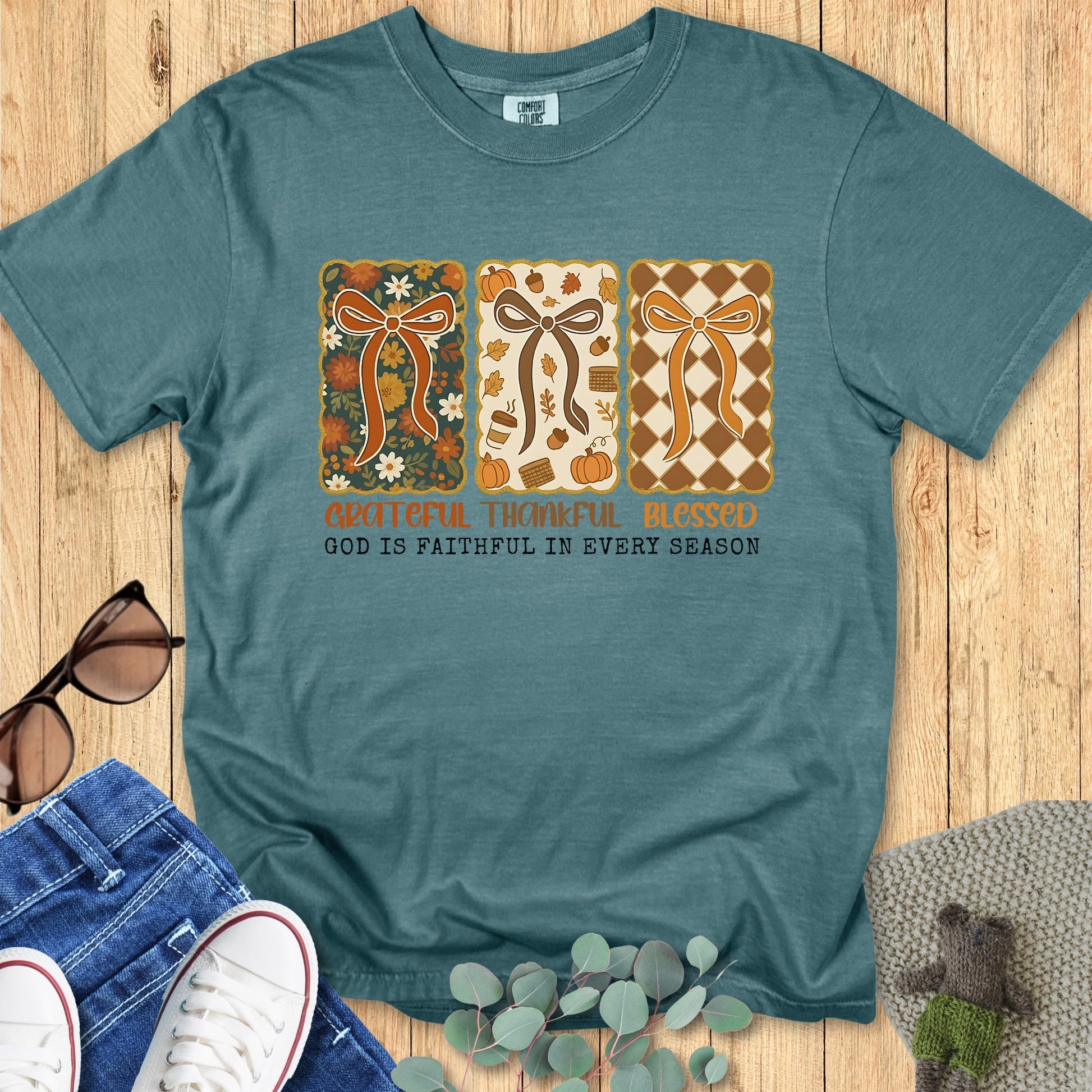 Flatlay of a Comfort Colors 1717 blue spruce “Grateful Thankful Blessed – God Is Faithful in Every Season” t-shirt with vintage patchwork bows and earthy tones. A stylish women’s scripture tee - faith-based apparel for women and modern Christian shirt, meaningful Christian mom gift idea for every season.
