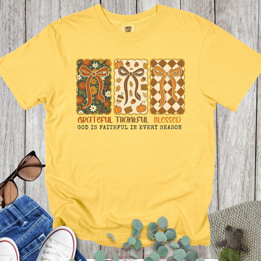 Flatlay of a Comfort Colors 1717 citrus “Grateful Thankful Blessed – God Is Faithful in Every Season” t-shirt with cheerful retro design and warm fall palette. A bright women’s scripture tee - faith-based apparel for women and modern Christian shirt, sweet Christian mom gift idea reminding her of God’s faithfulness.