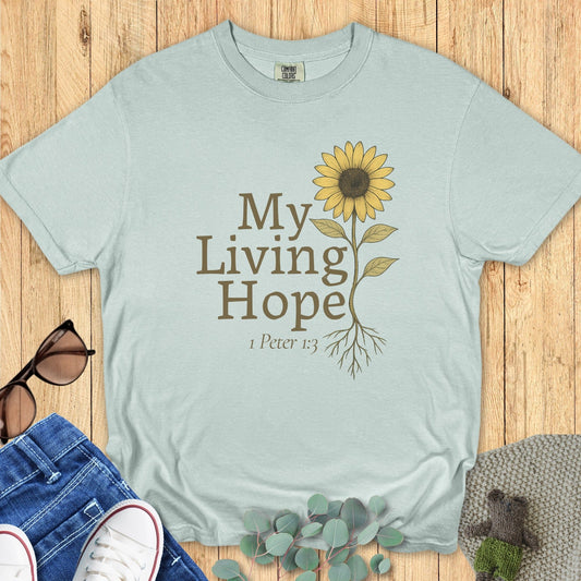 Flatlay of a Comfort Colors 1717 bay “My Living Hope – 1 Peter 1:3” t-shirt featuring a delicate sunflower graphic. A graceful women’s scripture tee — inspiring faith-based apparel for women and modern Christian shirt, lovely Christian mom gift idea.
