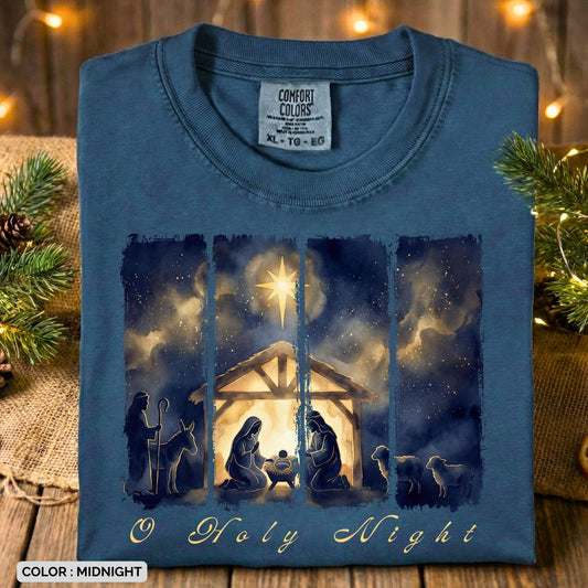 Folded Comfort Colors 1717 midnight Christian women’s T-shirt displaying a rich watercolor “O Holy Night” manger scene with the Holy Family, shepherds, and glowing star. A beautiful Christmas US faith wear tee arranged with rustic holiday décor.