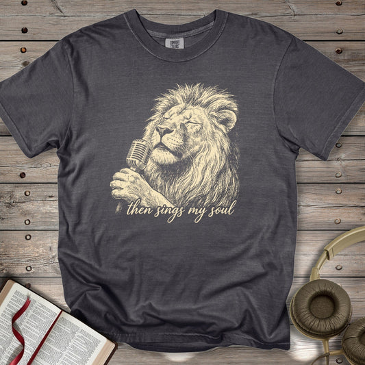 Pepper Grey Comfort Colors 1717 tshirt displaying a detailed sketch of a lion holding a microphone. "Then Sings My Soul" Christian women tee styled with a Bible and headphones, representing modern US faith wear.