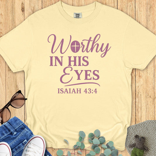 Comfort Colors 1717 Christian women’s t-shirt in butter yellow featuring the faith-based design 'Worthy in His Eyes – Isaiah 43:4' in bold purple lettering, styled with casual flat lay props including sunglasses, jeans, and sneakers.