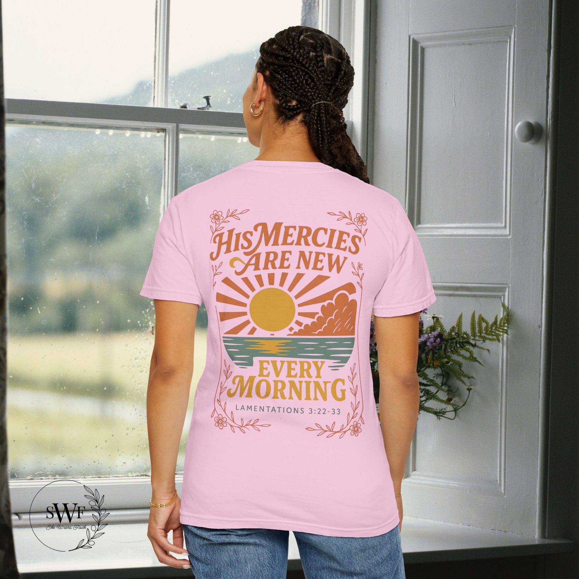 Back view of a light pink blossom Christian t-shirt with floral accents and a sunrise graphic reading “His Mercies Are New Every Morning – Lamentations 3:22–33.”