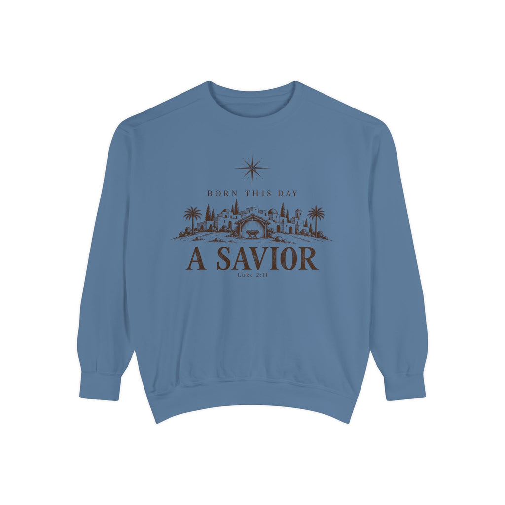 Blue Jean Christian Christmas sweatshirt with Born This Day A Savior lettering, a star over a Bethlehem town scene, a manger and Luke 2:11.