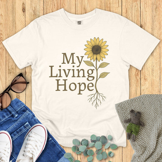 Ivory White t-shirt with sunflower design and 'My Living Hope' text on a wooden surface with accessories.