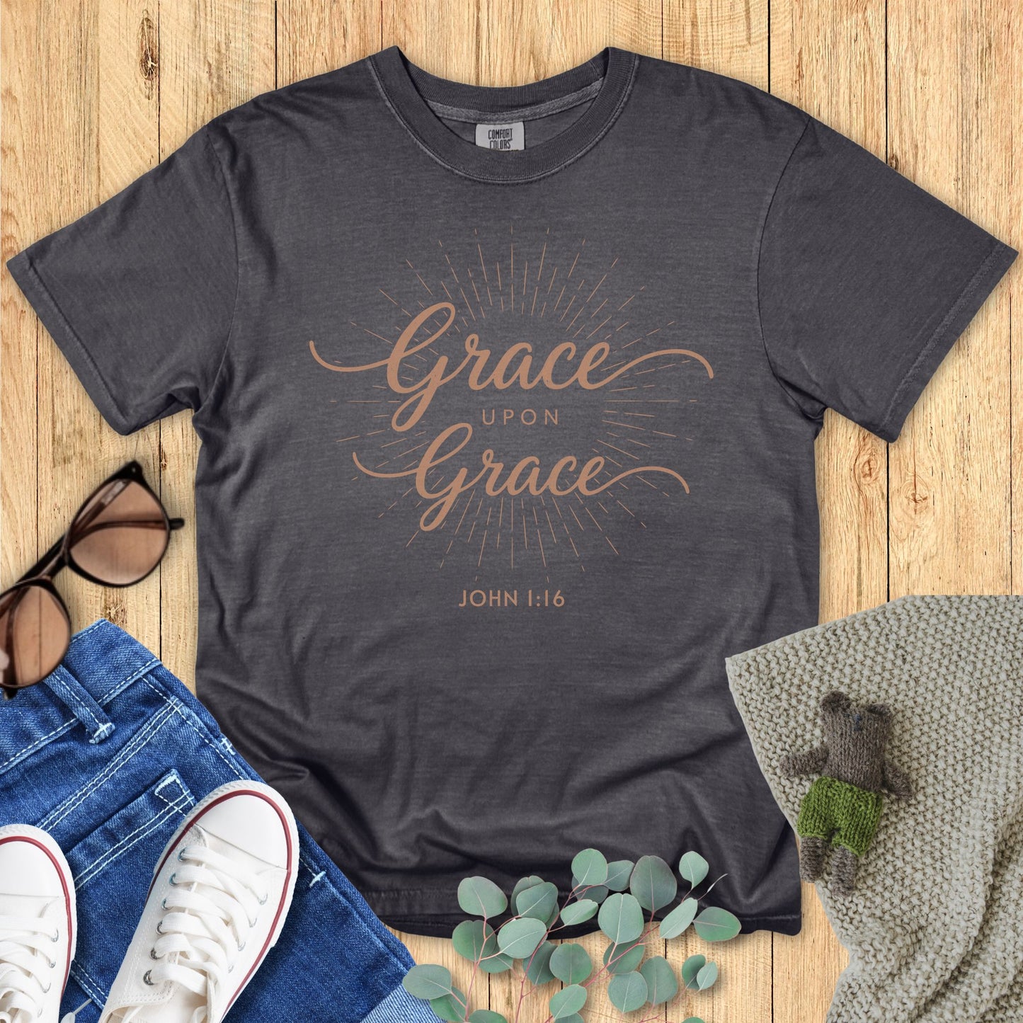 Gray t-shirt with 'Grace Upon Grace' text on a wooden surface with accessories.