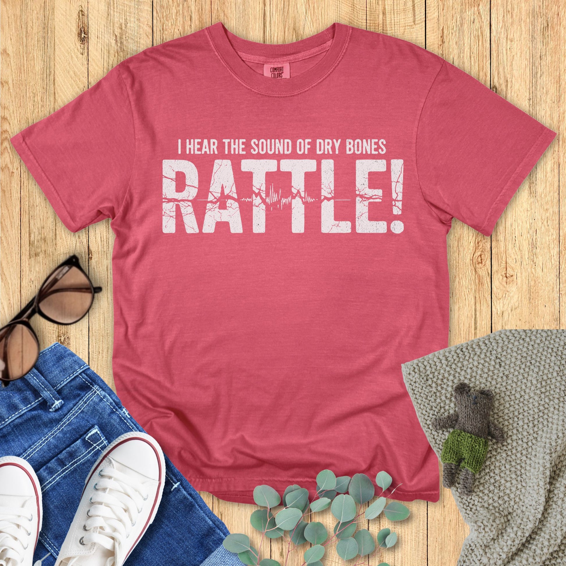Crimson Red t-shirt with text on a wooden surface with accessories around