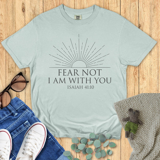 Light blue t-shirt with 'Fear Not, I Am With You' text on a wooden surface with accessories.