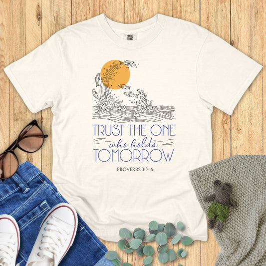 Ivory White t-shirt with motivational quote and design on a wooden surface with accessories.