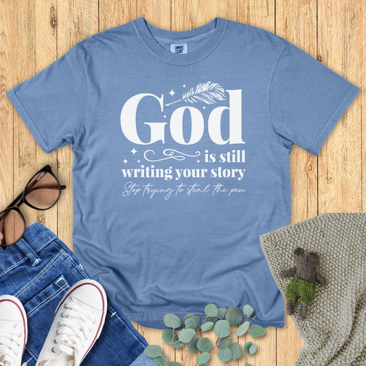 Blue t-shirt with motivational quote on a wooden surface with accessories.
