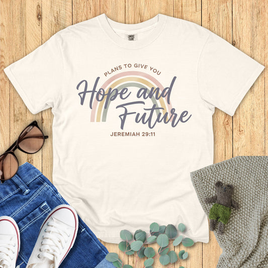 White t-shirt with motivational quote on a wooden surface with accessories.