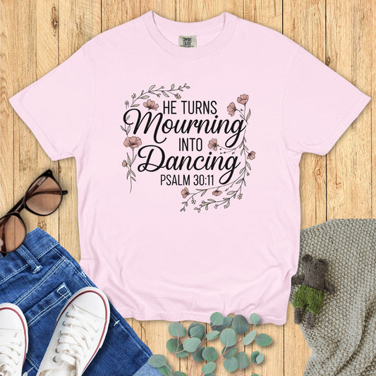 Pink t-shirt with motivational quote on a wooden surface with accessories.