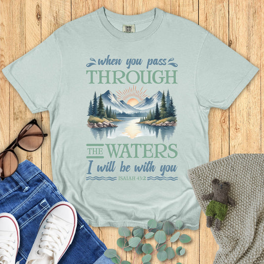 Light blue t-shirt with nature-themed design and text on a wooden surface with accessories.