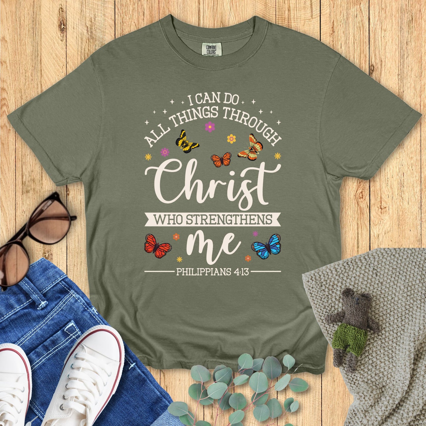 Green t-shirt with motivational quote on a wooden surface with accessories.