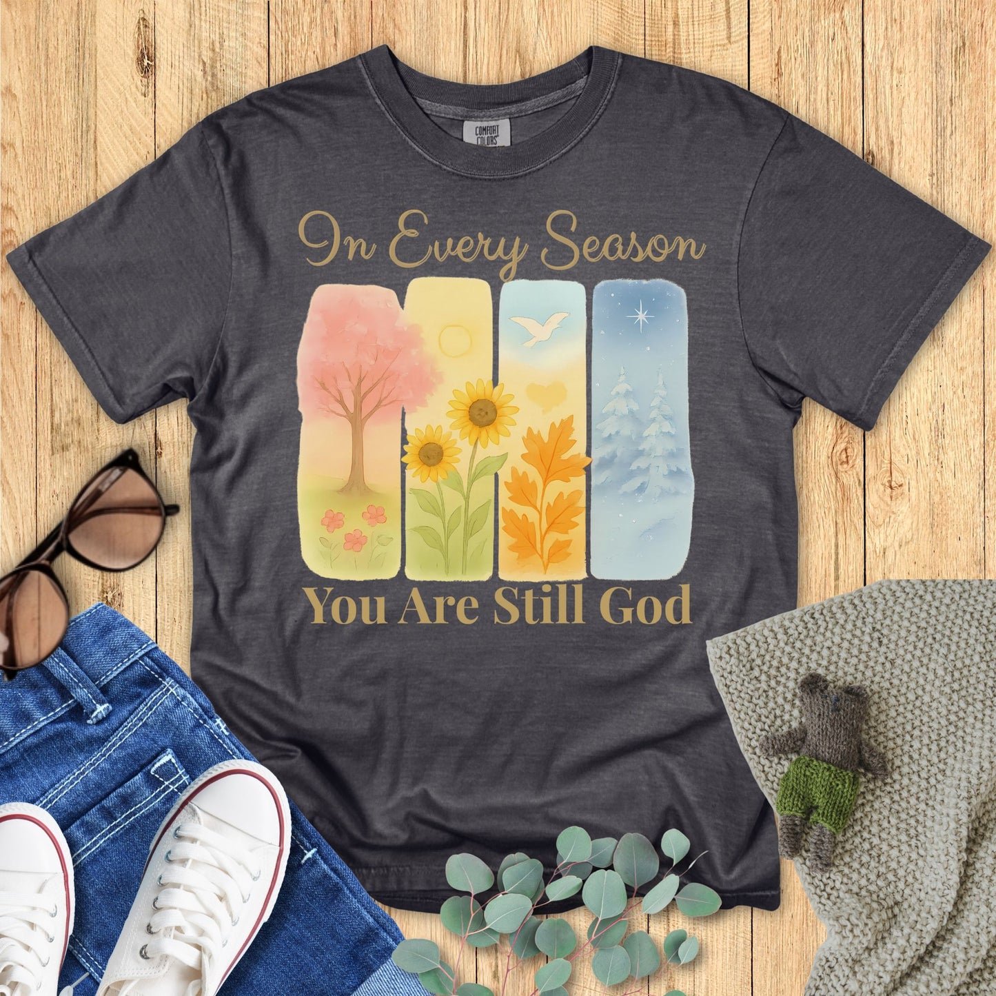 Dark gray t-shirt with colorful graphic and text on a wooden surface with accessories.