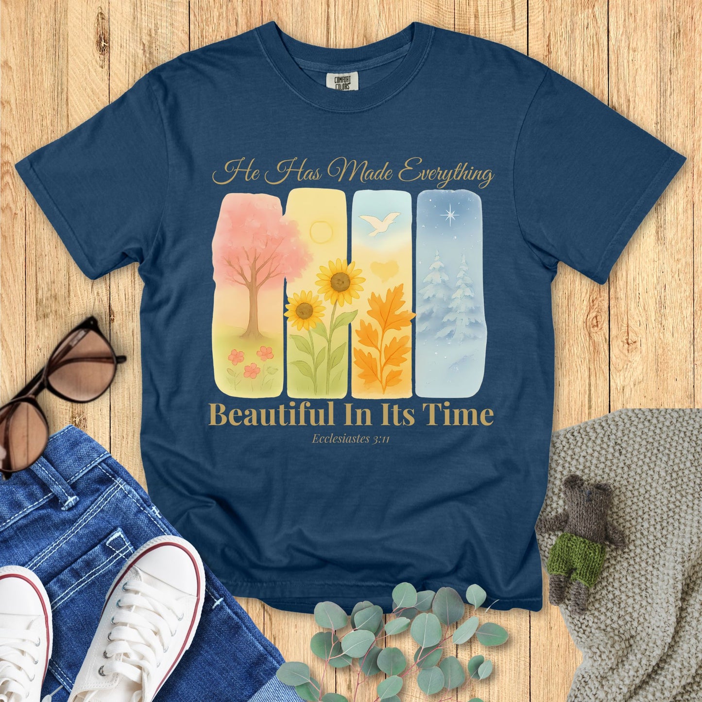 Navy blue t-shirt with colorful design and text on a wooden surface with accessories.