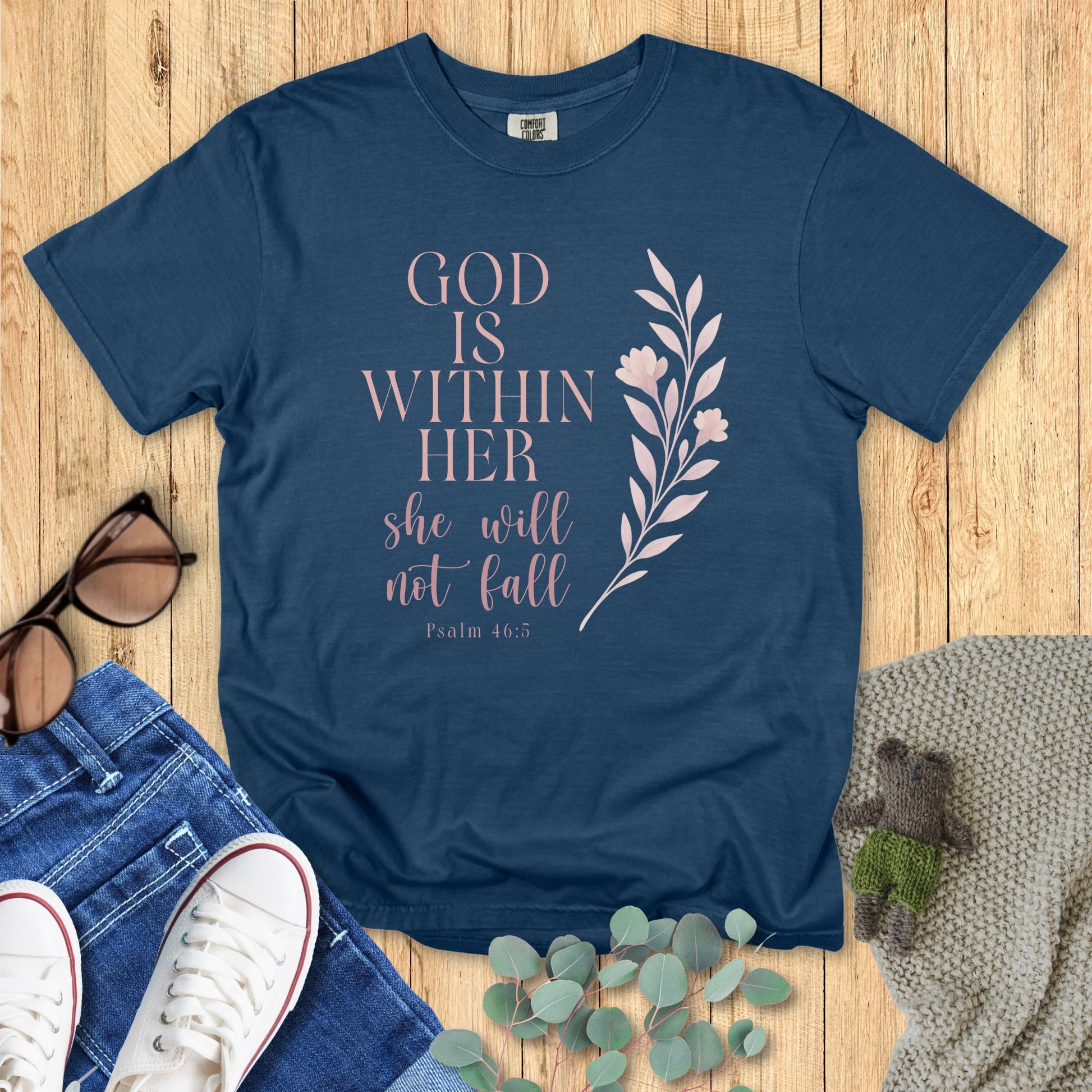Blue t-shirt with motivational quote on a wooden surface with accessories.