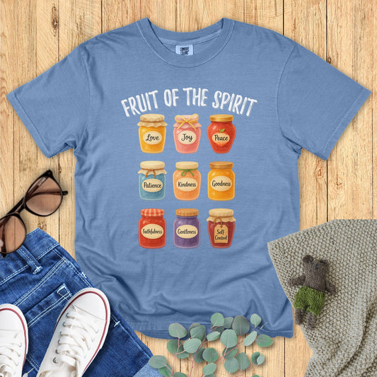 Blue t-shirt with jelly jar design and 'Fruit of the Spirit' text on a wooden surface.