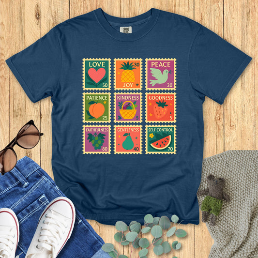 Blue t-shirt with colorful graphic design on a wooden surface with accessories.