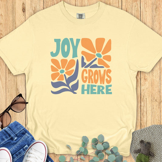 Joy Grows Here graphic printed on a Comfort Colors 1717 Butter t-shirt – retro floral design with orange, teal, and lavender accents
