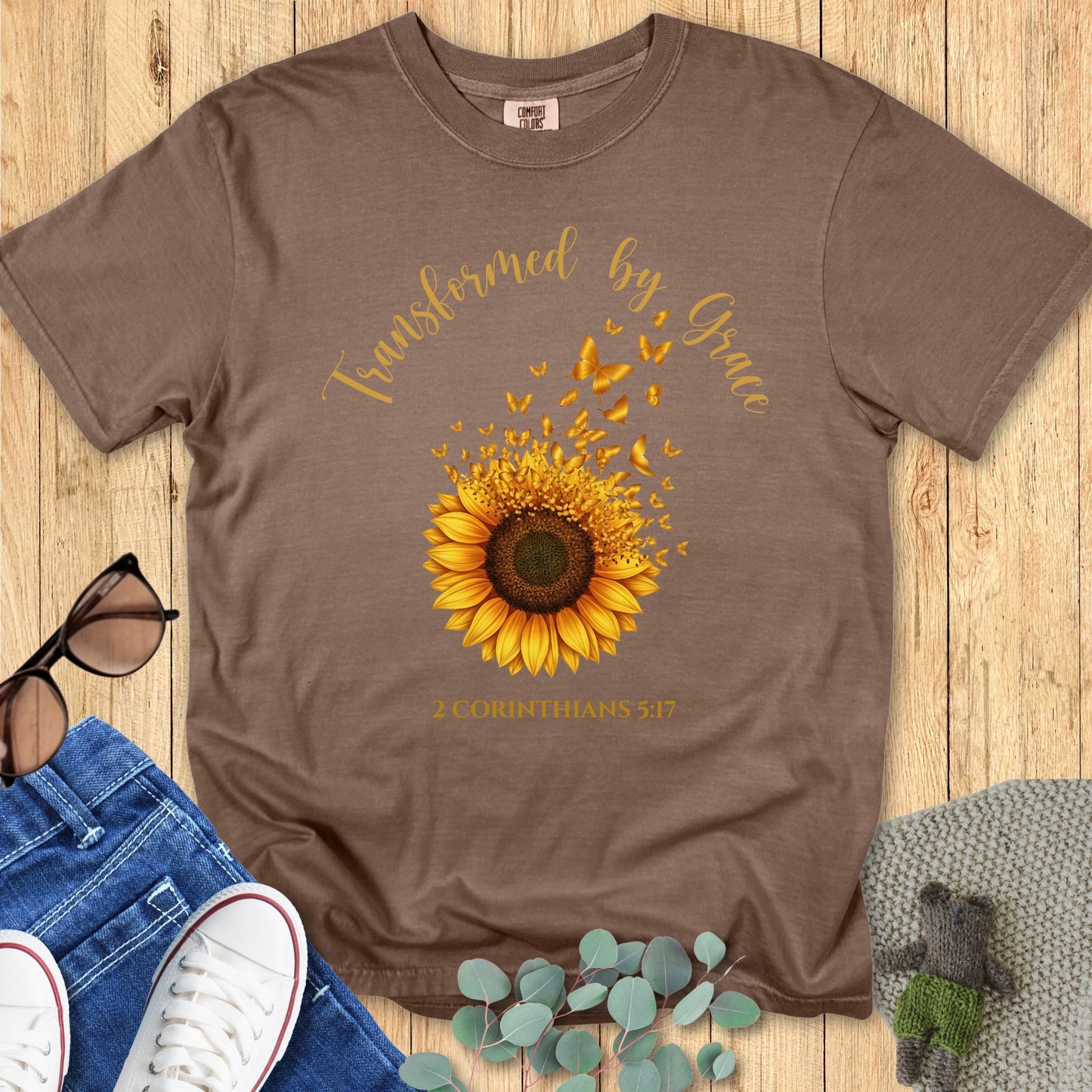 Comfort Colors 1717 Christian women t-shirt in espresso brown flat lay. Sunflower and butterfly Christian design with the verse “Transformed by Grace – 2 Corinthians 5:17