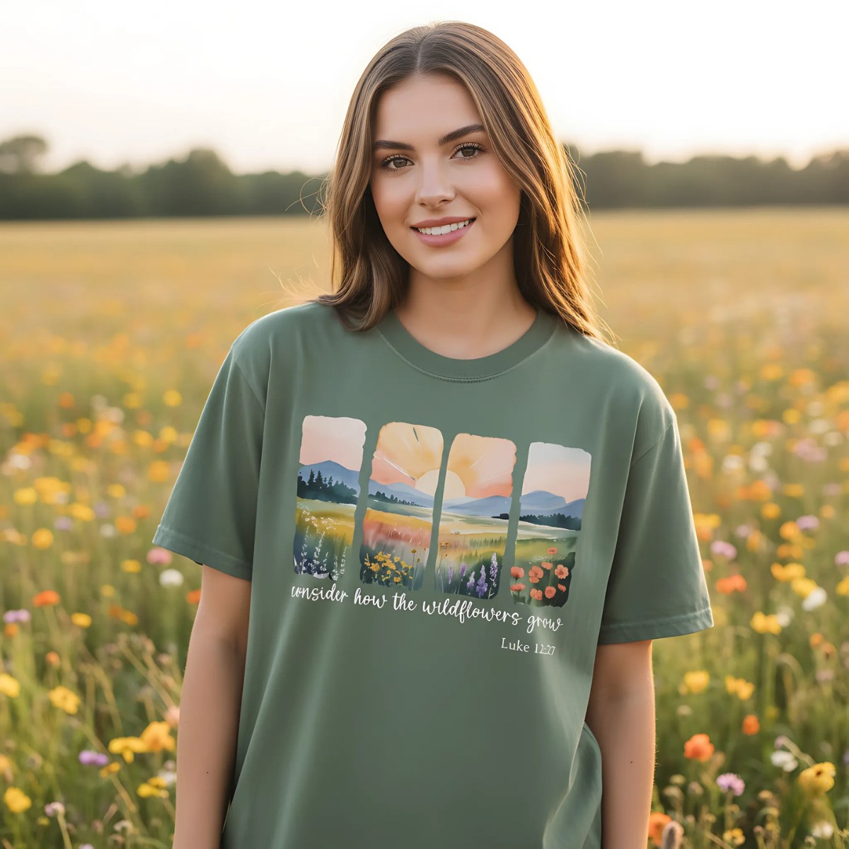 Young woman standing in a field of wildflowers at sunset wearing a moss green T-shirt with a watercolor-style four-panel landscape design, text “Consider how the wildflowers grow – Luke 12:27