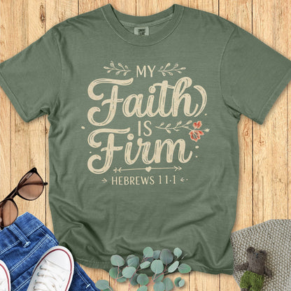 Comfort Colors 1717 moss green Christian women’s t-shirt with the faith-based quote ‘My Faith Is Firm – Hebrews 11:1’ in cream script and floral accents, styled flat lay with jeans, sunglasses, and eucalyptus