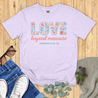 Orchid purple Comfort Colors Christian T-shirt featuring floral block letter "LOVE," phrase "beyond measure," and scripture Romans 8:38–39. Religious inspirational graphic tee flat lay styled with denim and accessories.