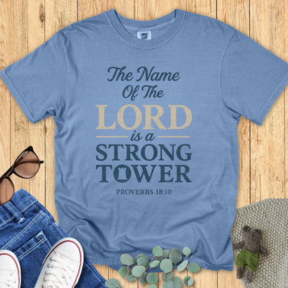 Comfort Colors 1717 blue jean “The Name of the Lord is a Strong Tower – Proverbs 18:10” t-shirt flatlay on wooden background with denim and cozy accessories. A timeless design from modern Christian shirts collection.